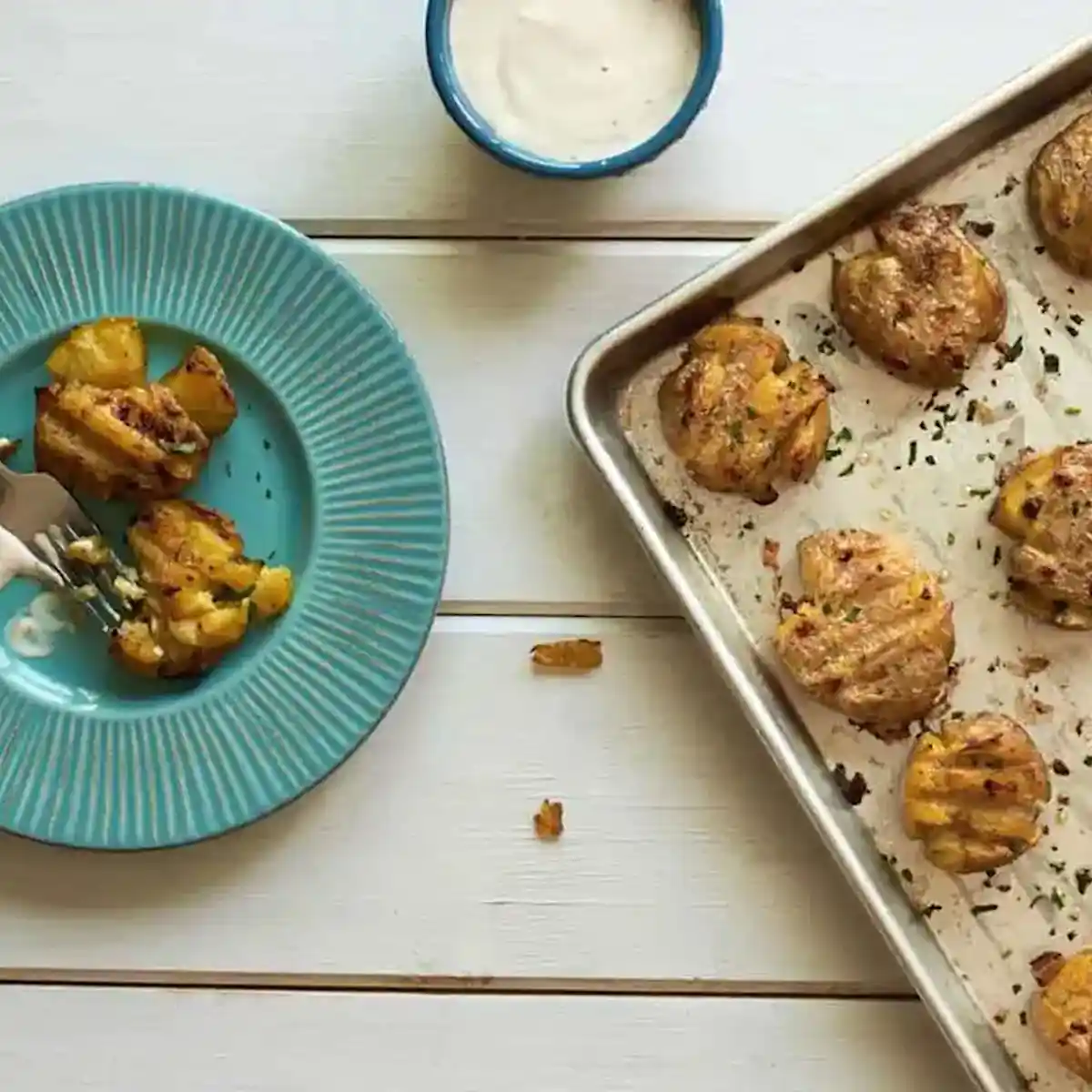 Smashed potatoes on a baking sheet and on a blue plate
