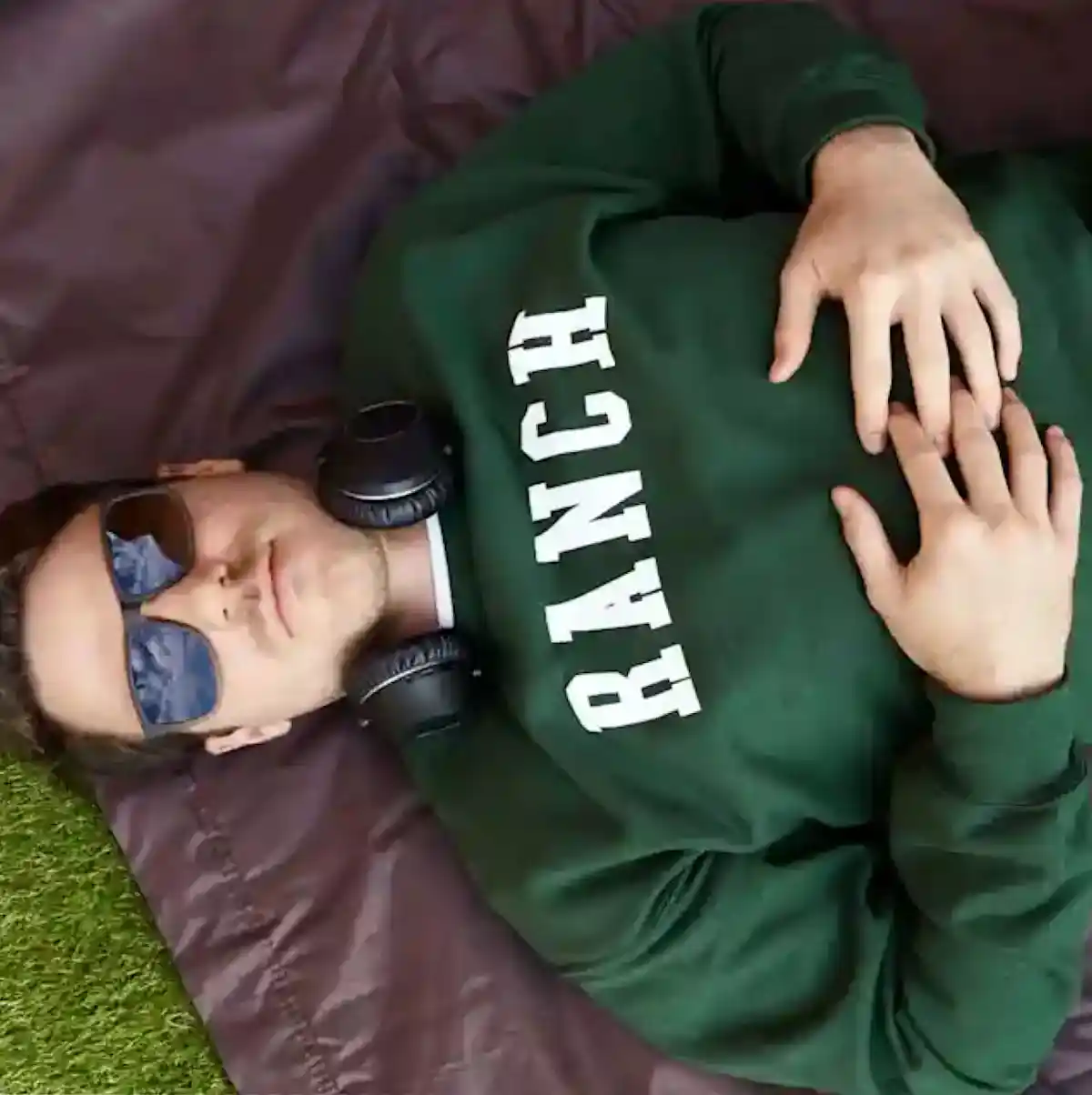 An overhead shot of a person in sunglasses wearing a green sweatshirt with the word "ranch" in white