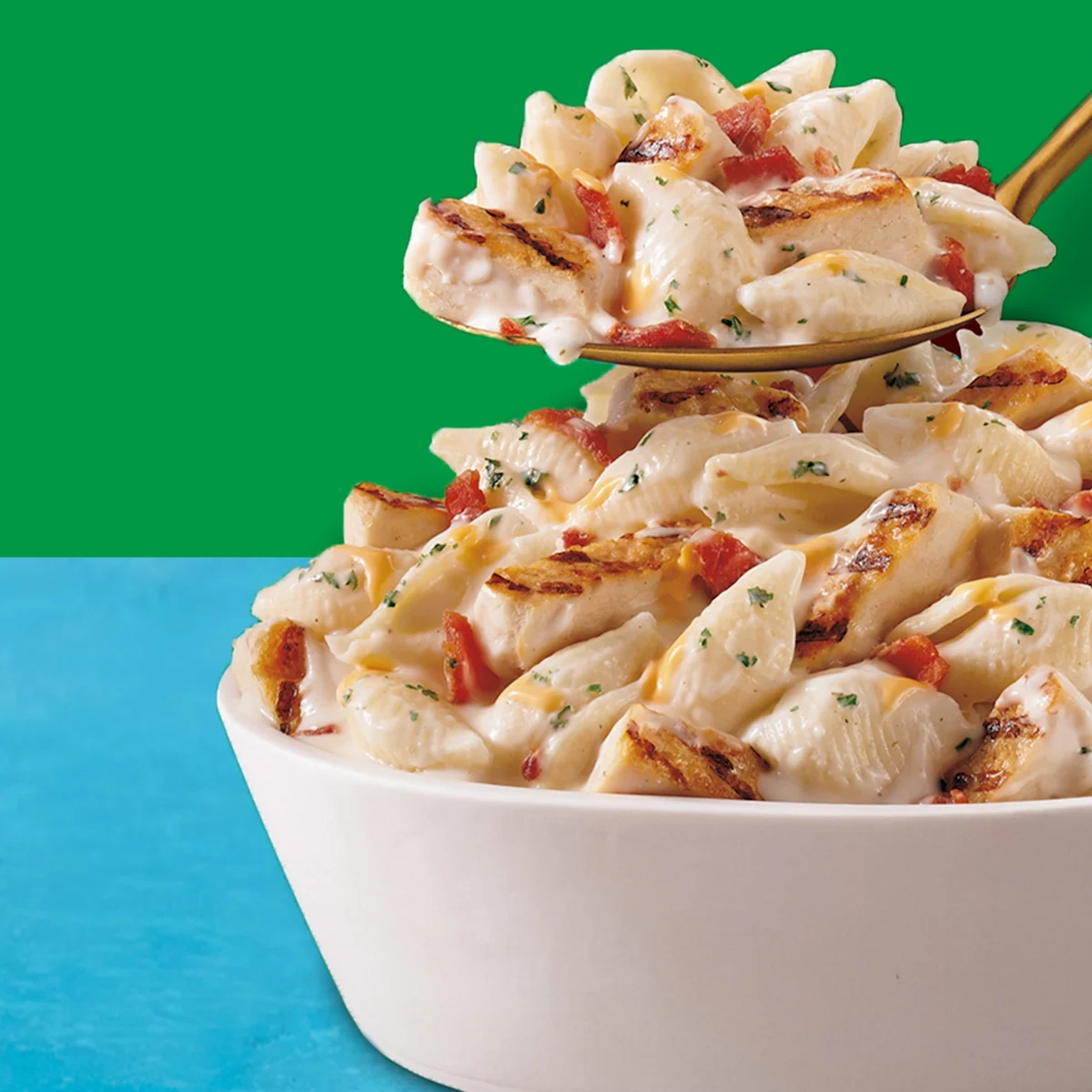 Chicken bacon ranch pasta in a white bowl with a spoonful of pasta hovering over the bowl