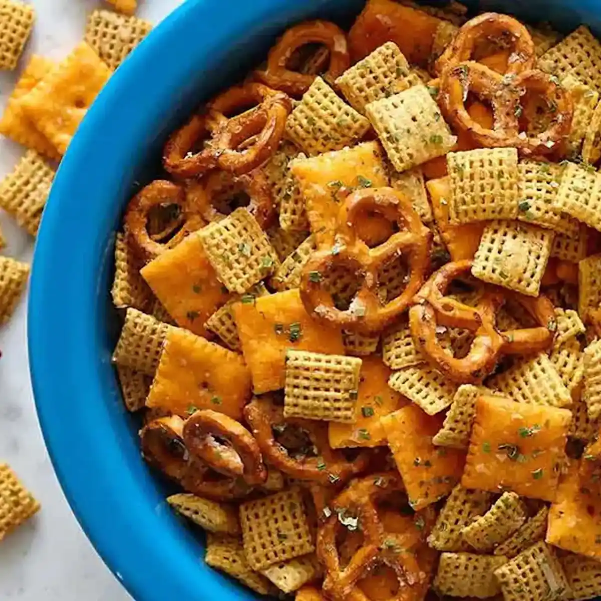 Wheat squares, cheese squares, pretzels in a blue bowl