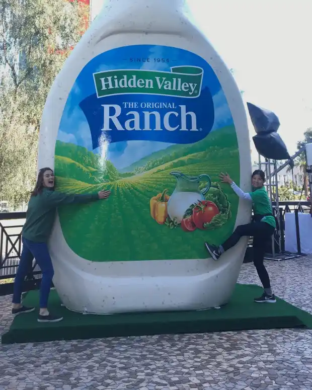 Two people hugging a large inflatable bottle of Hidden Valley Ranch