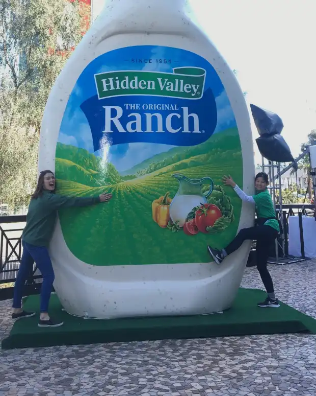 Two people hugging a large inflatable bottle of Hidden Valley Ranch
