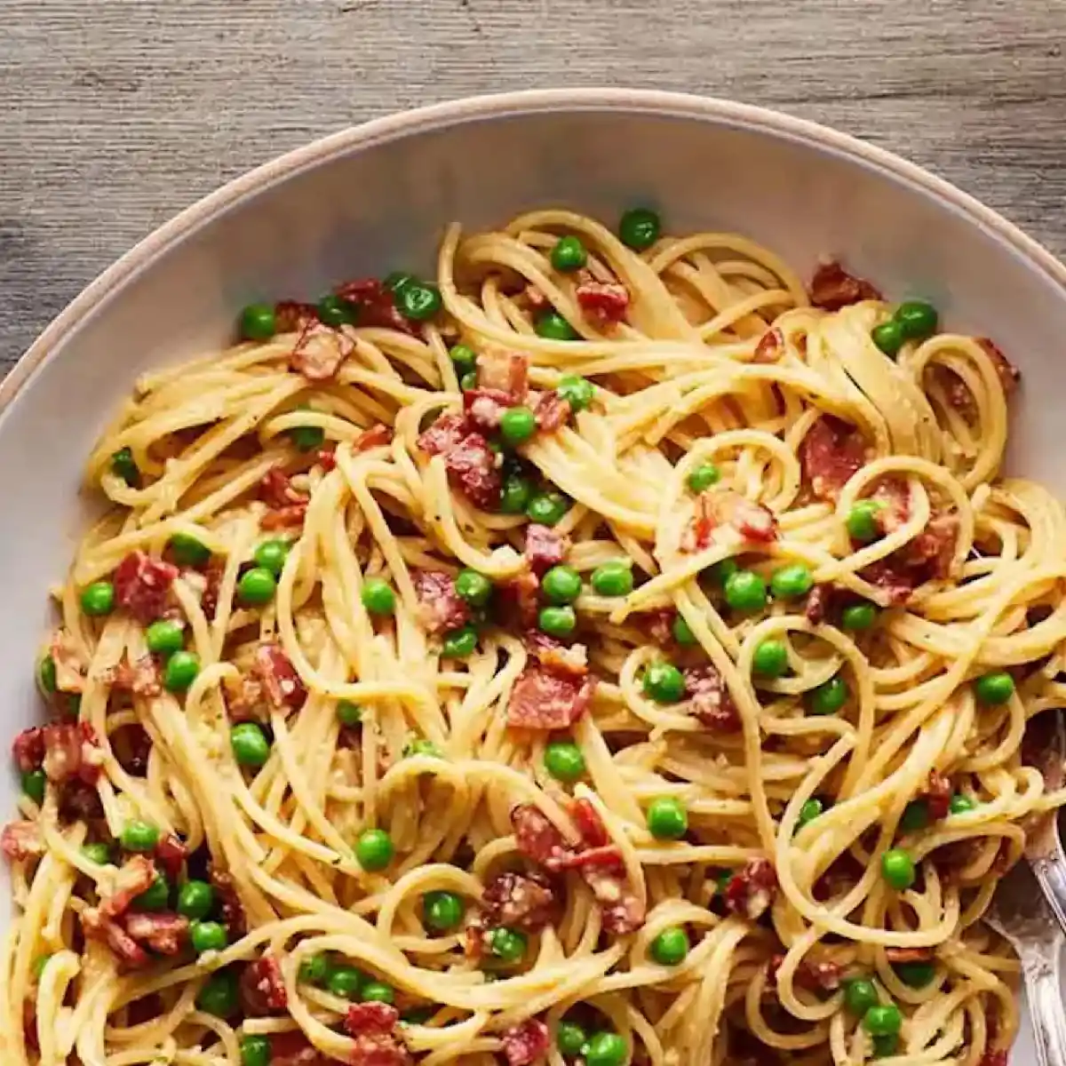 Noodles in a bowl with peas and bacon