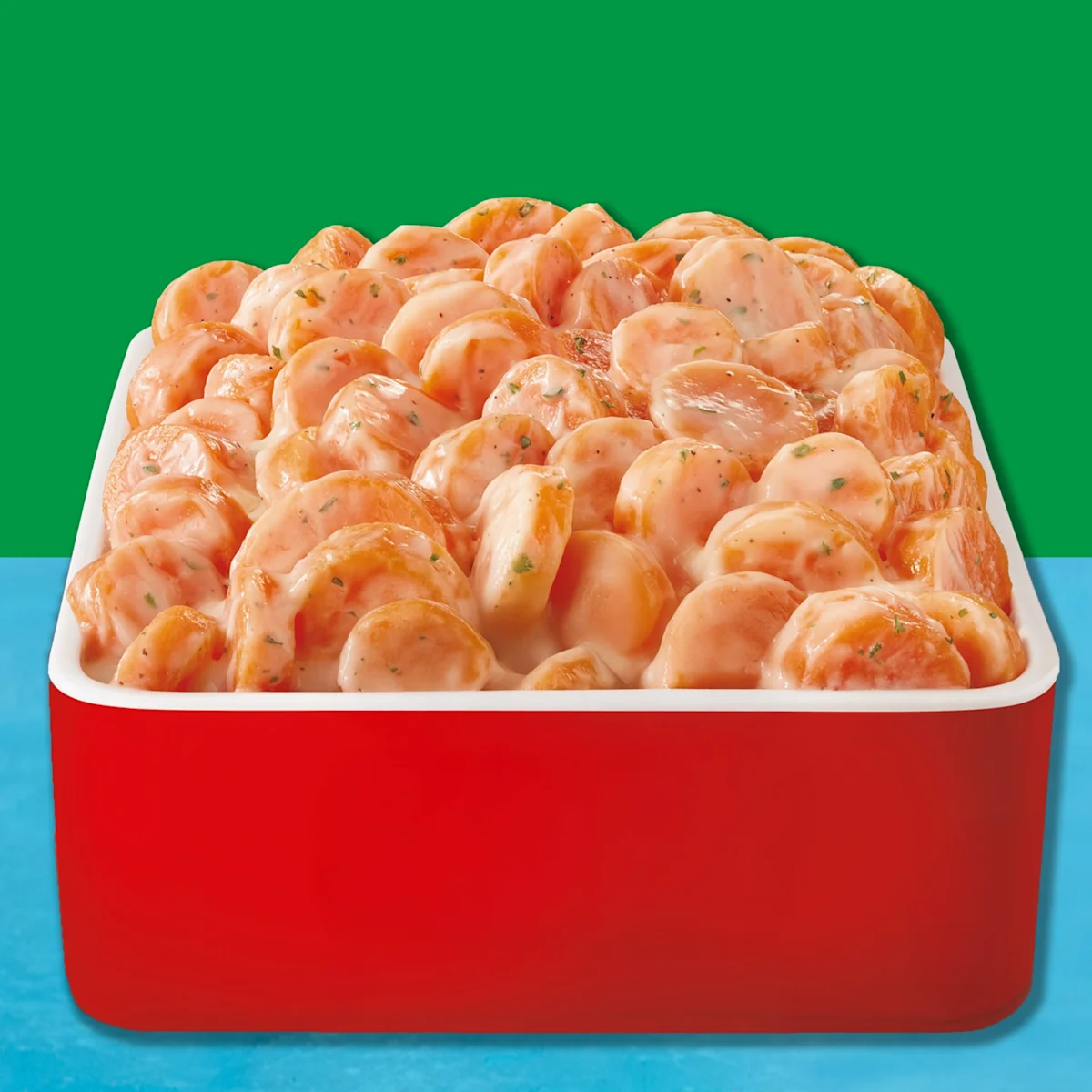 Sliced carrots covered in Ranch dressing in a red dish with a blue and green background