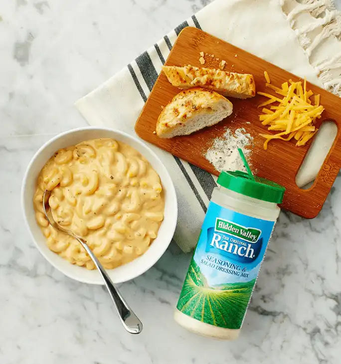 macaroni and cheese with ranch seasoning shaker on a marble countertop