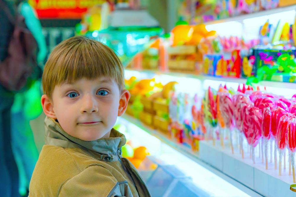 Kid-Looking-At-Toys-in-the-Candy-Aisle-of-an-American-Candy-Shop 1583222527