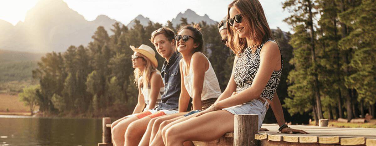 A group of young adults sat by a lake discussing the benefits of private medical insurance