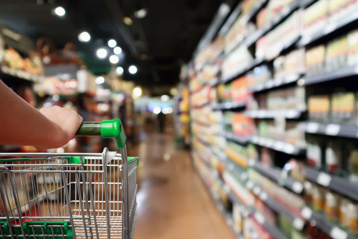 A trolley in a supermarket is empty while people try and learn how to save money nz