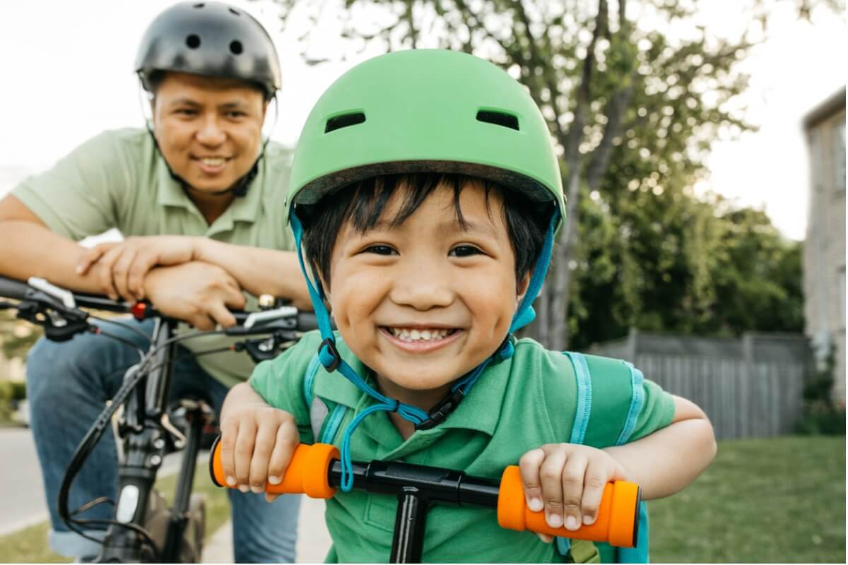 Father and son smiling on a bike ride showcasing what it's like to have happy healthy kids