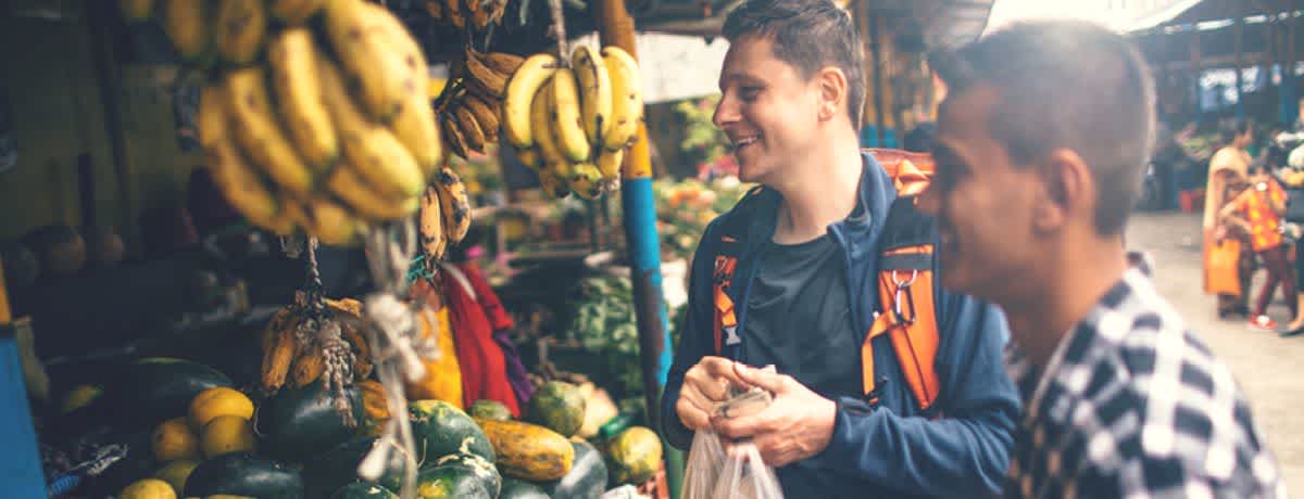 A man at a fruit market smiling before getting sick on holiday