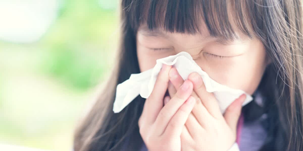 A little girl blows her nose into tissue struggling with hayfever, one of the 10 most common illnesses