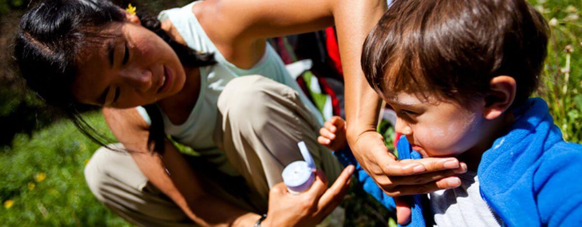 Mother applies sunblock to kids' face knowing the importance of sun safety NZ