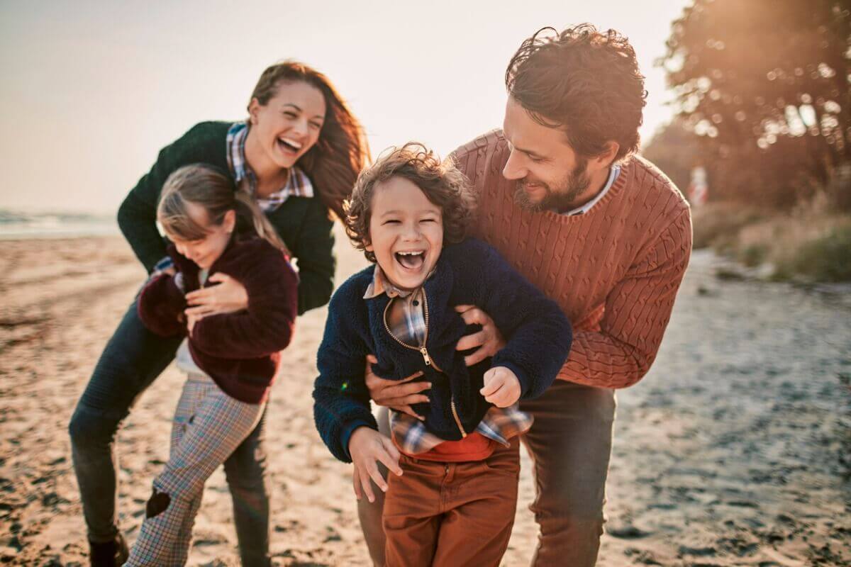 A family of four laugh and smile on a beach after completing an activity on their nz bucket list