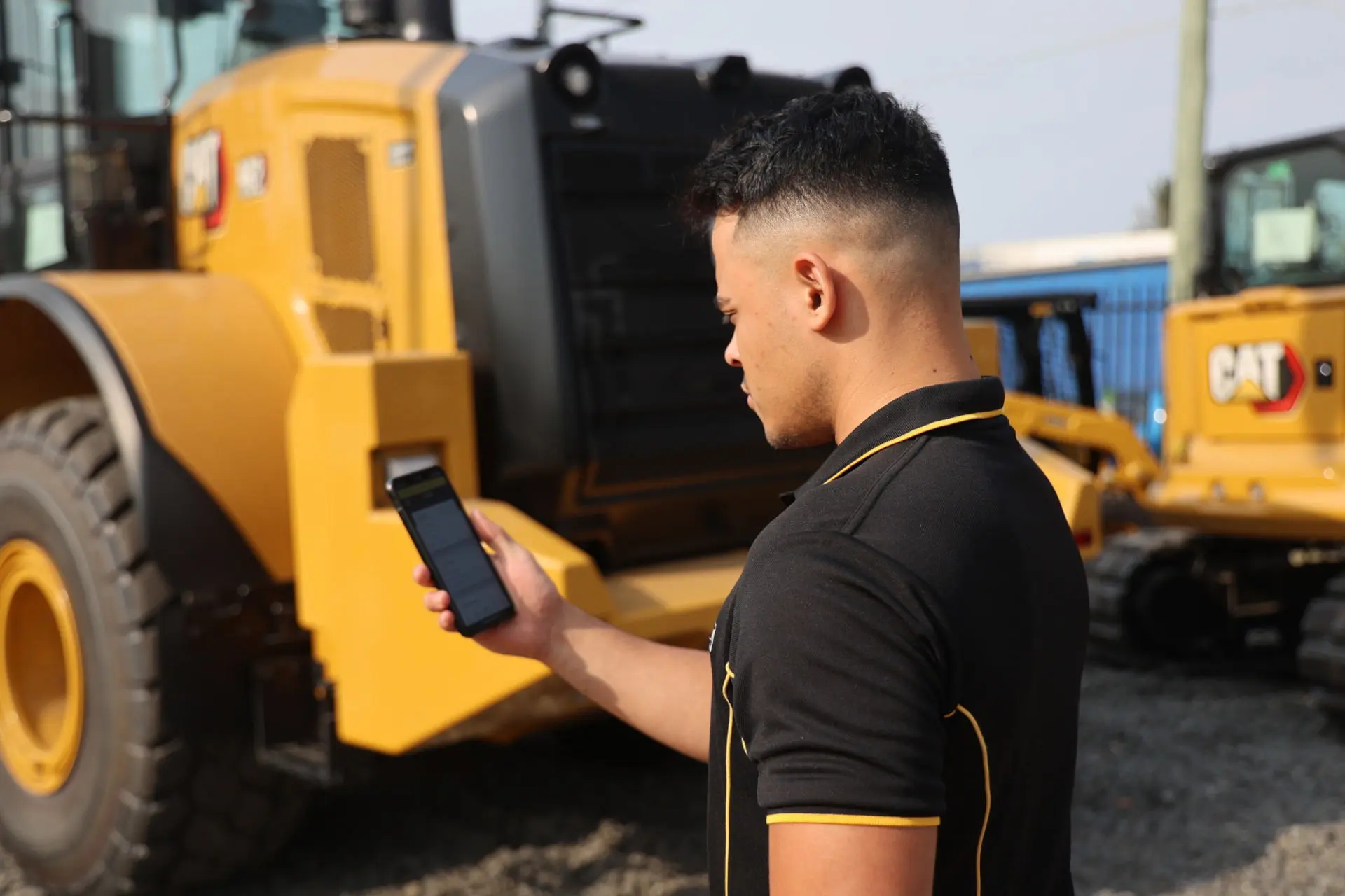 Hastings Deering Employee holding phone using HD360 with equipment 1920px q80