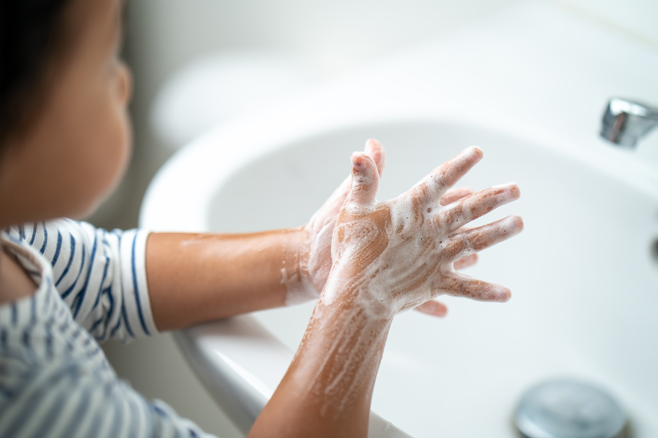 A small girl washing her hands in the bathroom sink