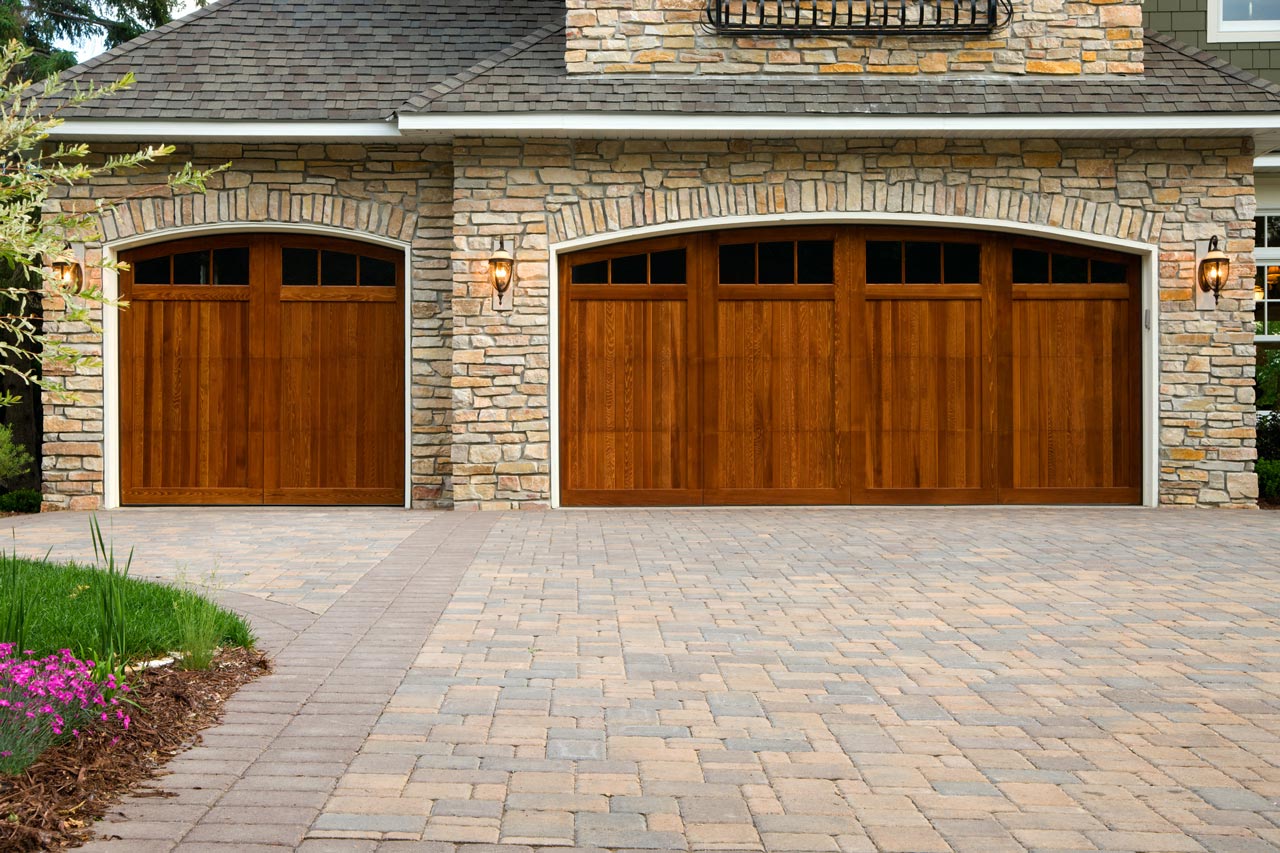 A driveway made of interlocking pavers leading to a beautiful house garage
