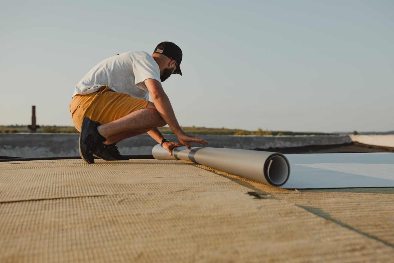 Worker applying pvc membrane roller on roof