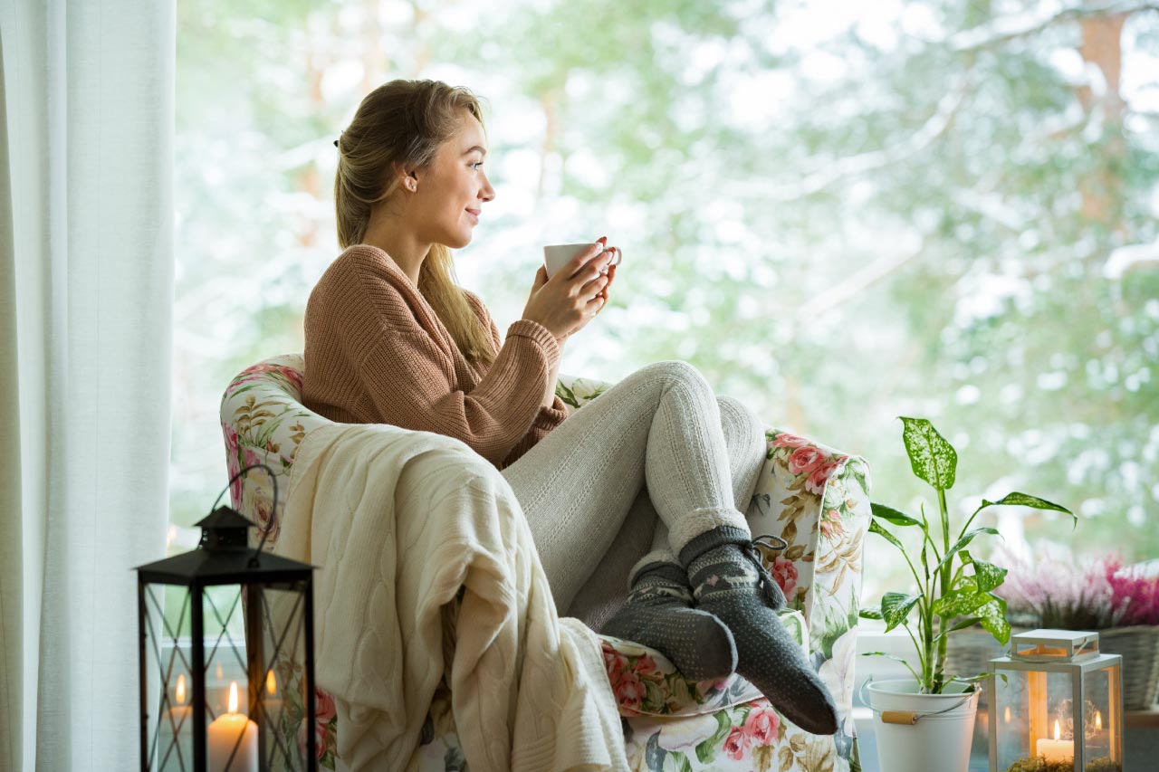 Woman sitting in a chair by the window with cup of coffee