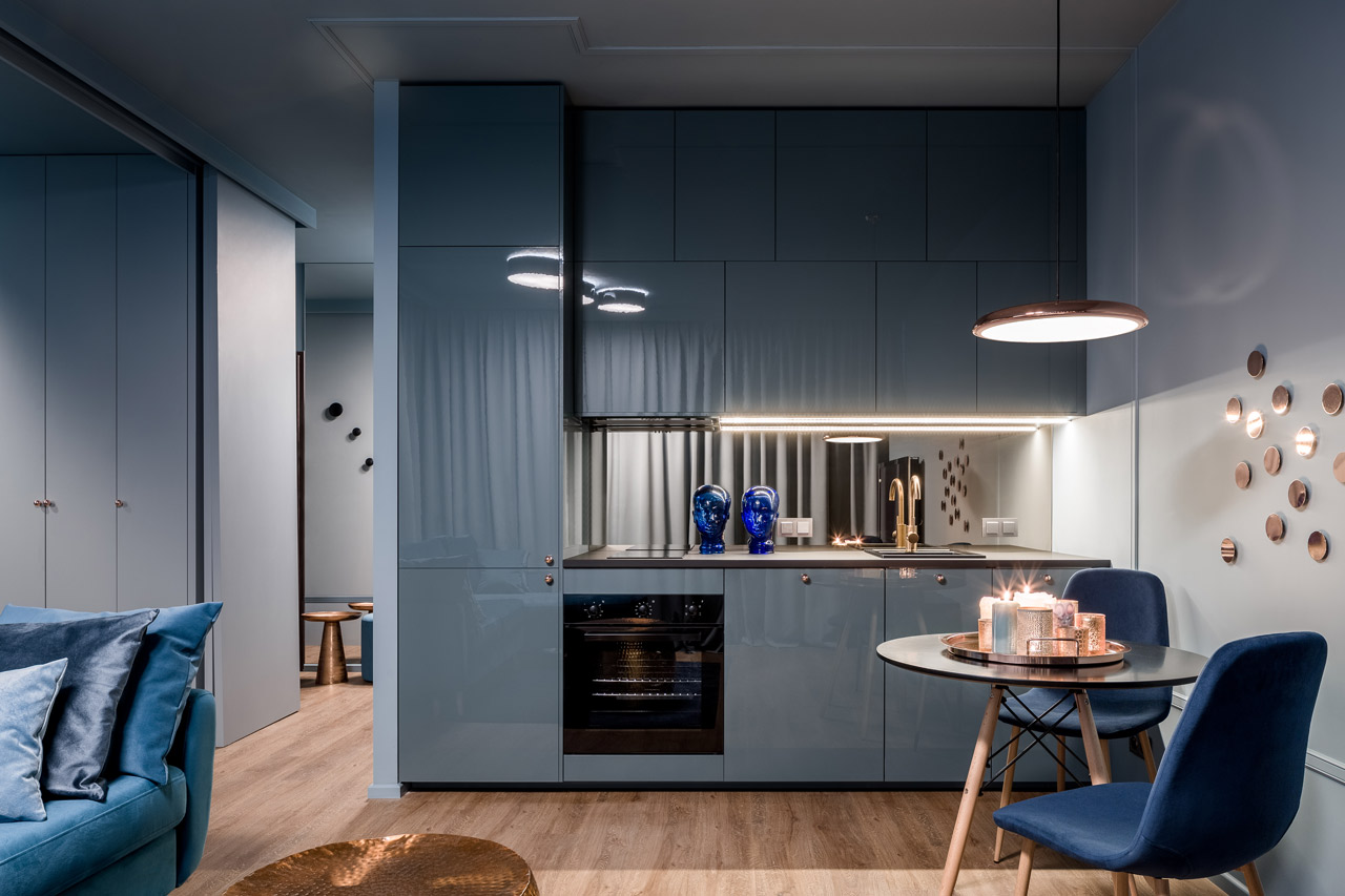 A dark blue open kitchen at night
