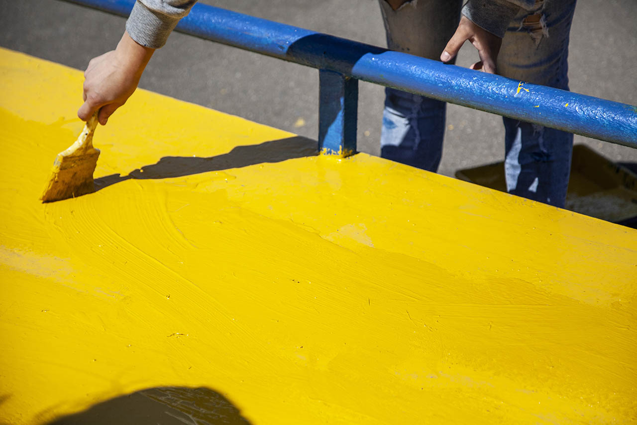 worker repairing and repainting playground equipment