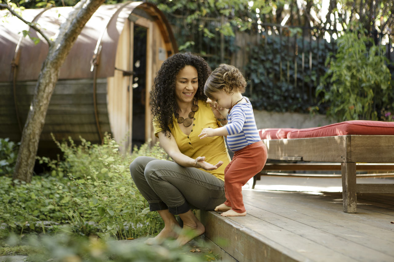 A mother helping her toddler step off the deck