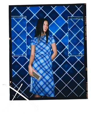 Suki holding Marshall speaker and standing against a blue patterned background.