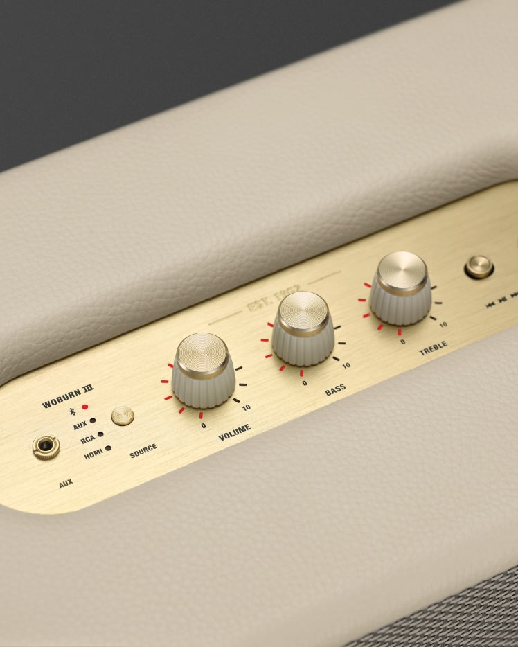 A close up of a Marshall Woburn III Cream speaker with gold buttons.