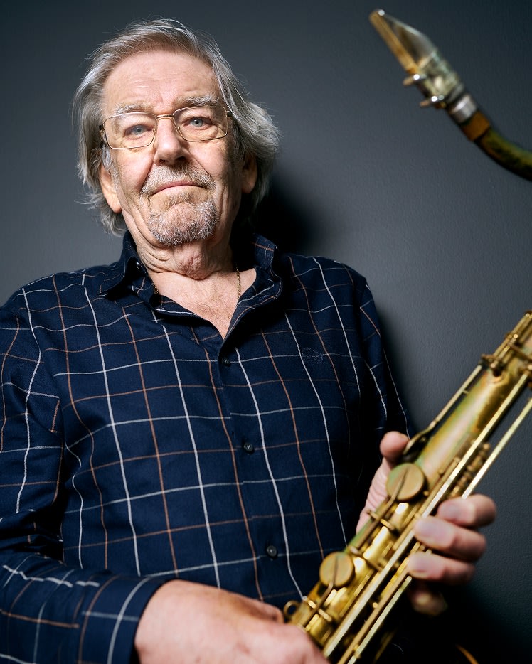 Terry Marshall wearing a dark blue shirt and holding a musical instrument.