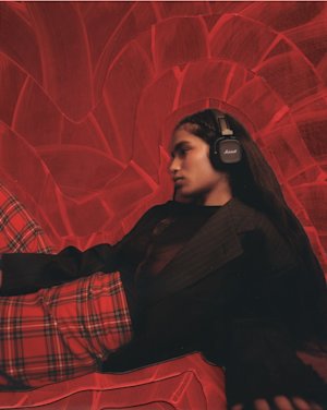 A girl listening to a over-ear headphone from Marshall.