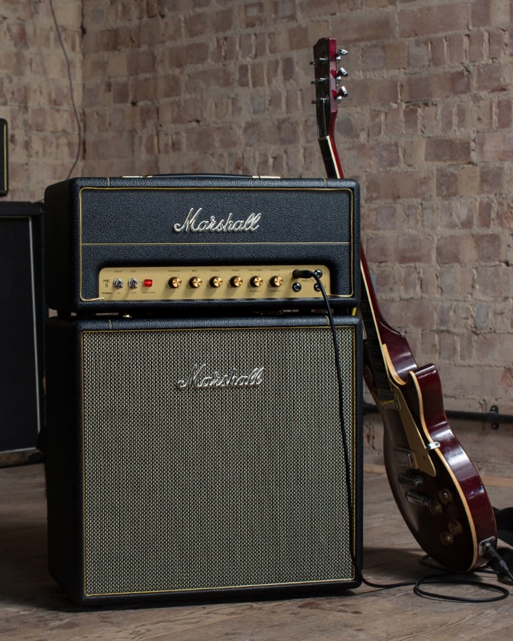 Marshall Studio Vintage Head amplifiers and guitars are displayed next to a brick wall.