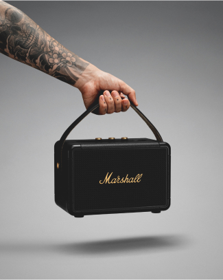 A hand holding a black Marshall KILBURN II portable speaker. 