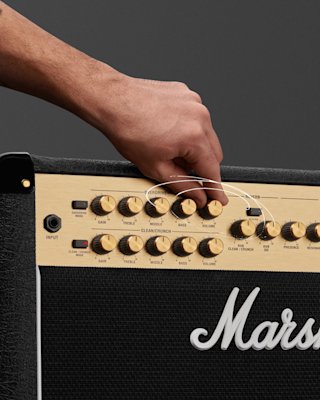 A person turning the control knobs of the Marshall JVM215 Combo amp.