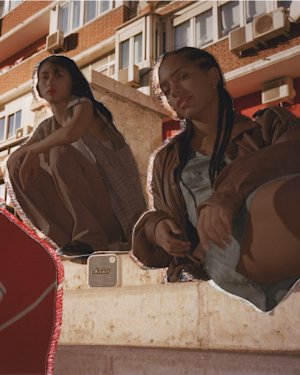 Tres personas sentadas en una cornisa disfrutando de música portátil desde un altavoz Marshall WILLEN.