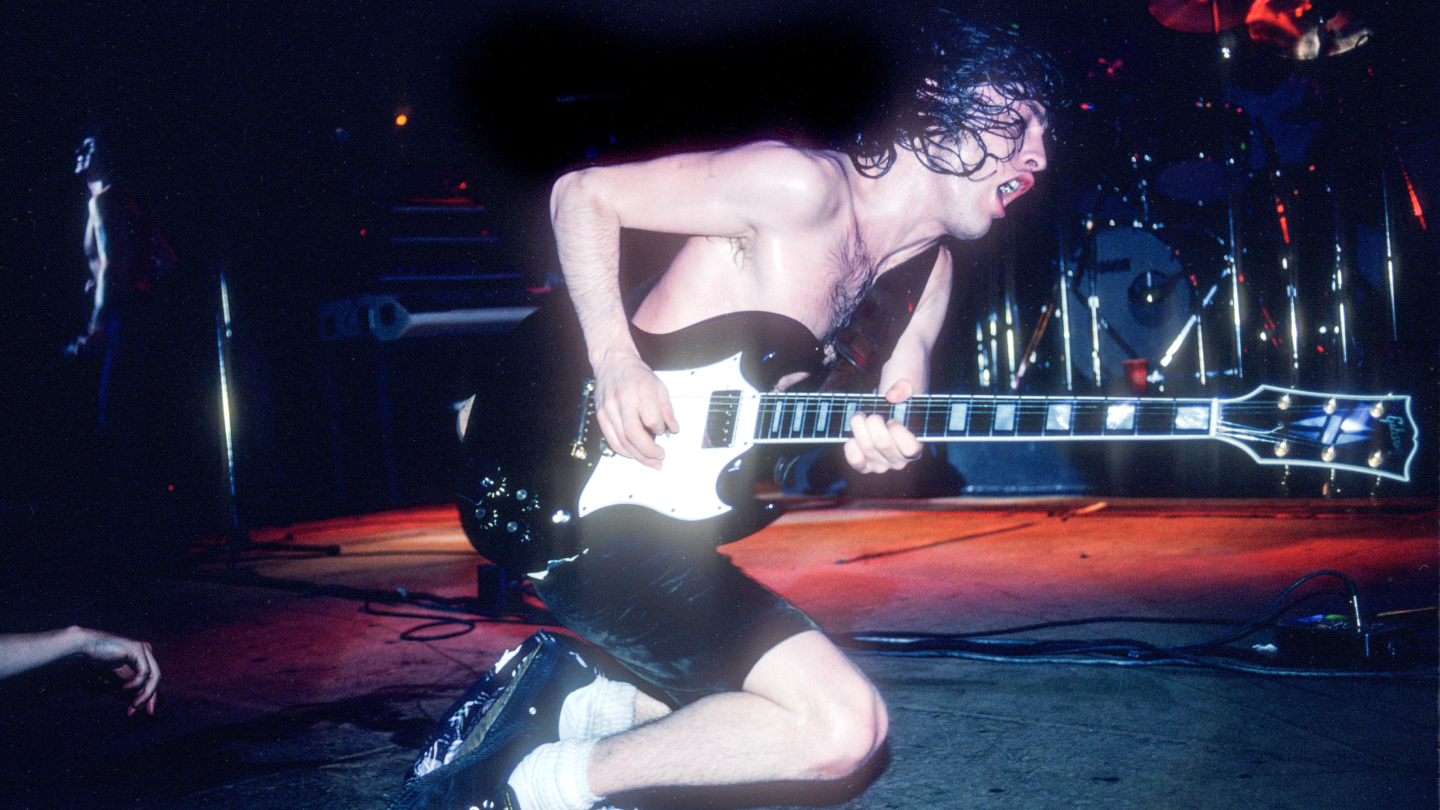 Angus Young performing on stage playing guitar