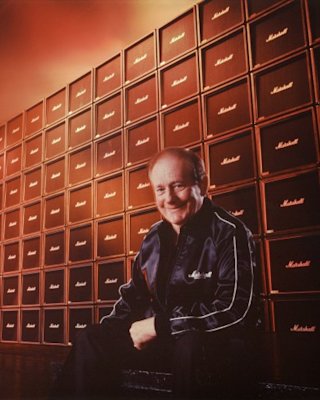 Jim Marshall sat in front of a wall of Marshall Cabs.