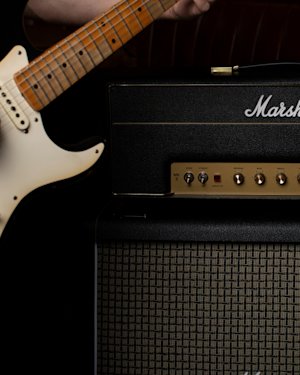 Una persona tocando la guitarra en un concierto con el mejor amplificador para un sonido crujiente.