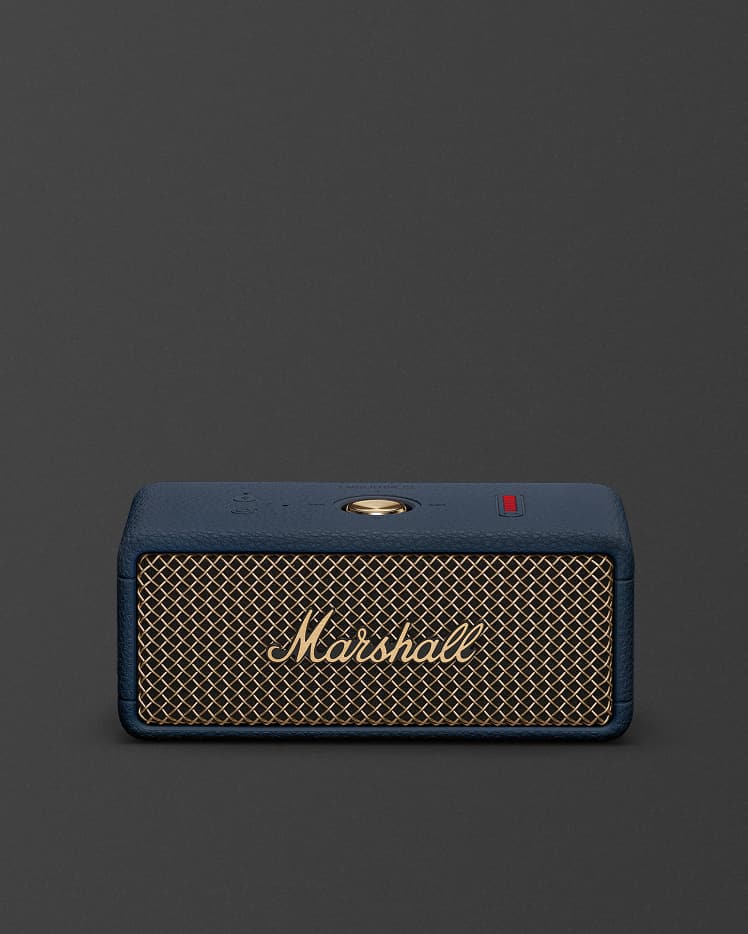 Marshall Emberton III Midnight Blue portable Bluetooth speaker, featuring a gold mesh front grille and navy blue casing, sits centered against a plain dark background.