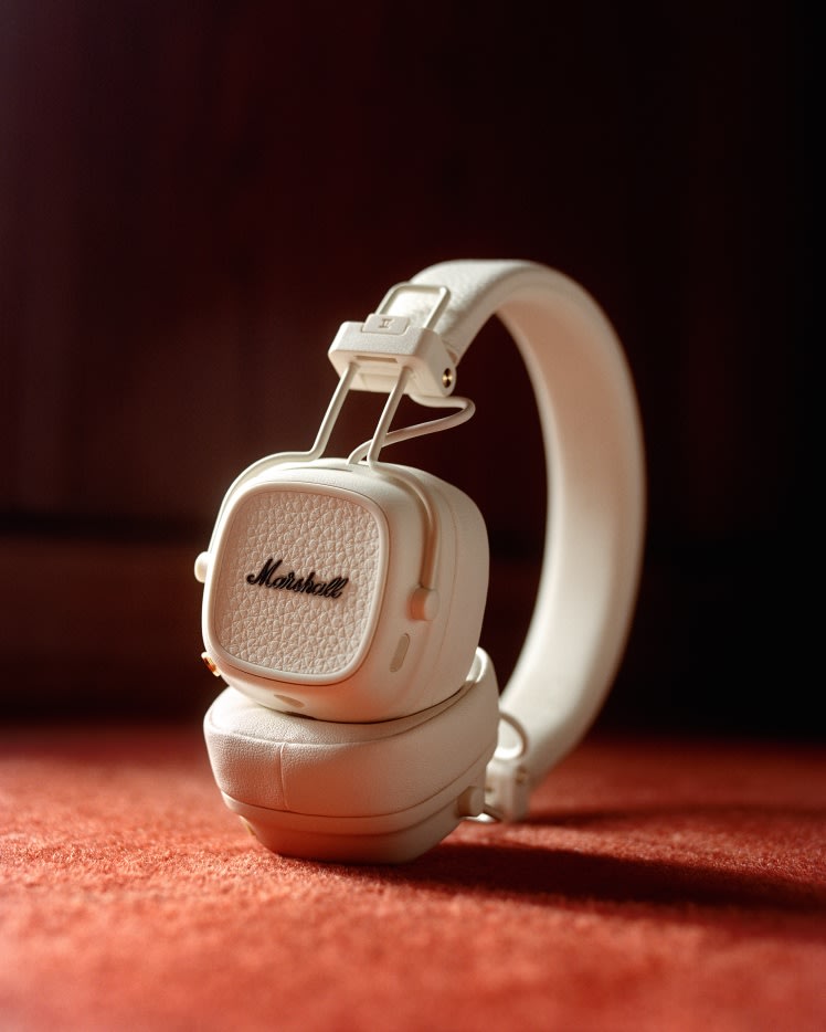 Marshall Major V Cream On-Ear-Kopfhörer auf einem dunklen Hintergrund mit reflektierenden Akzenten.