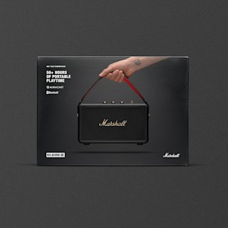 Marshall Kilburn III portable Bluetooth speaker packaging, showing a hand holding the speaker by its red strap against a black background.