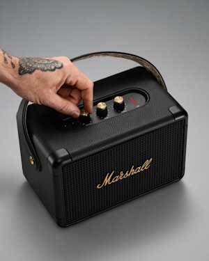 Hand with tattoos turning the volume knob on the Kilburn II speaker.