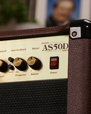 A man sitting on a chair with a Marshall AS50D amplifier combo.