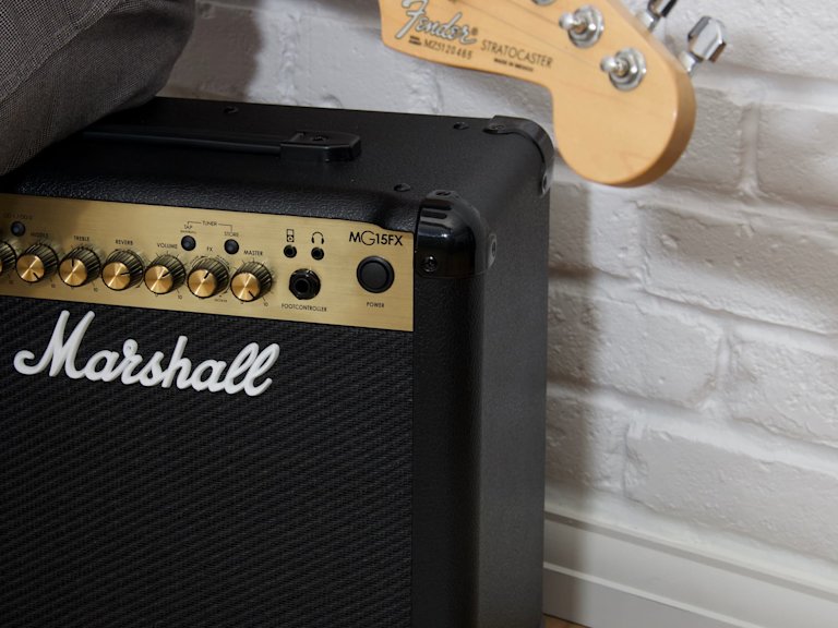 Una persona sentada encima del amplificador combo Marshall MG15FX