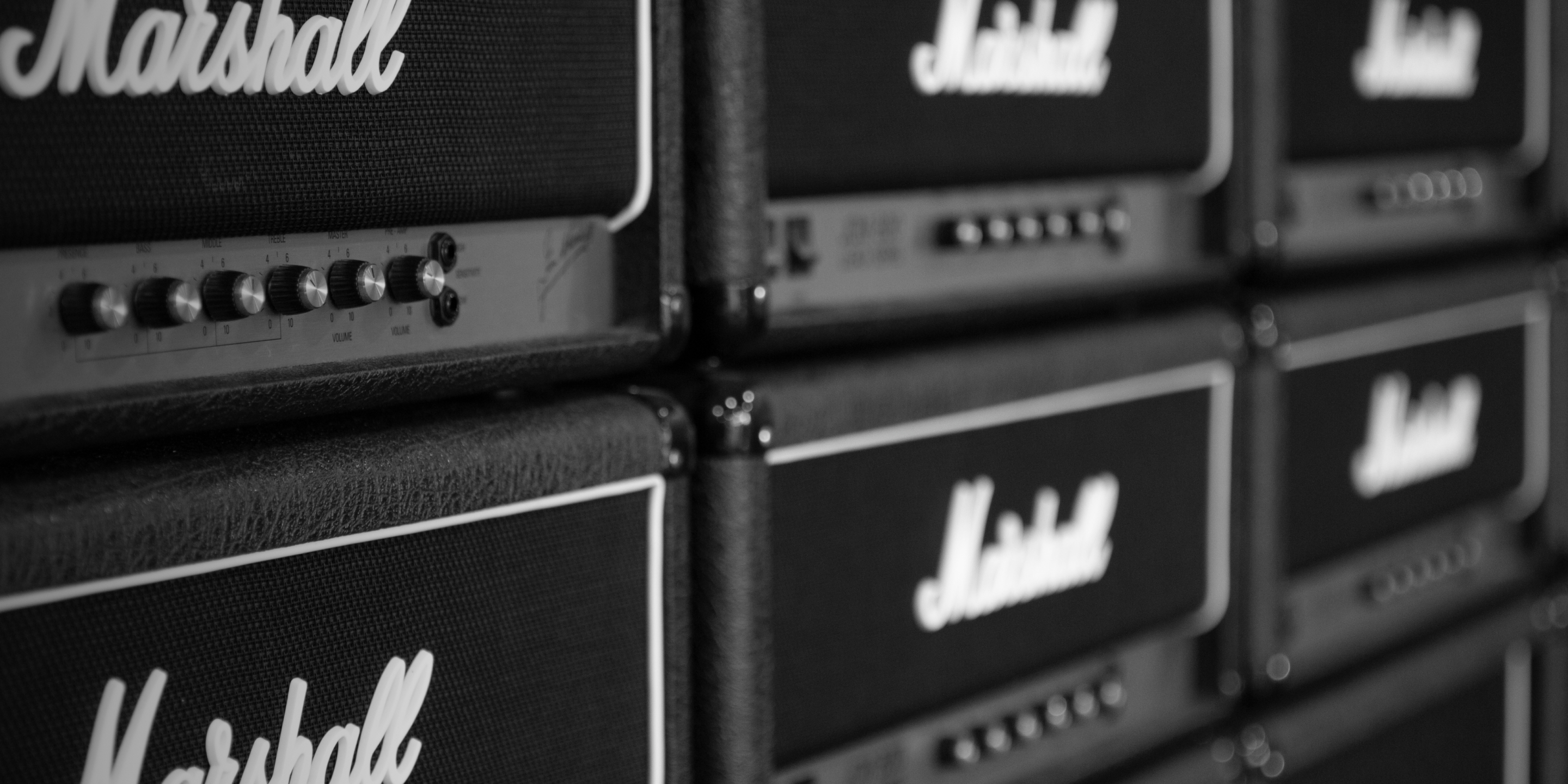 Close-up of stacked Marshall head amps with visible control knobs and logos.