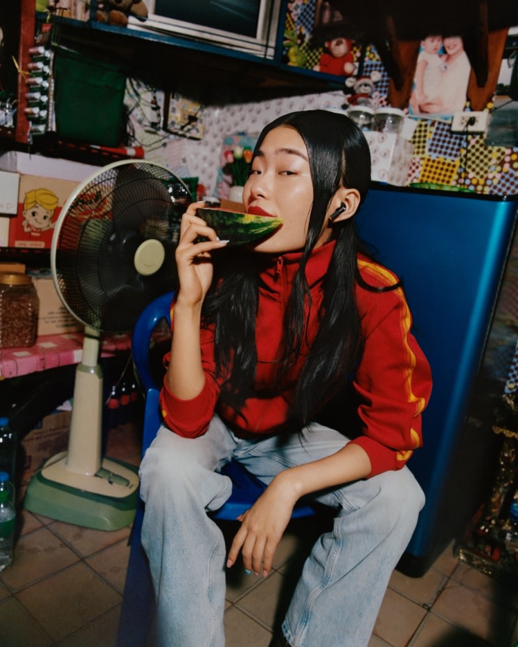 スイカを食べながらMarshall Minor IV Blackトゥルーワイヤレスイヤホンを装着する女性。