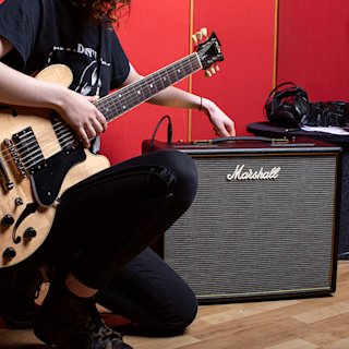 Un guitarrista tocando conectado al CODE25 en una habitación roja