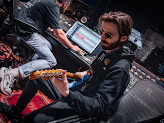Ein Bassgitarrist übt das Spielen auf einer blauen Gitarre im Marshall Studio