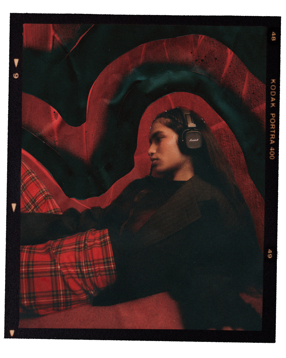 Woman with Marshall Major V Black on-ear headphones against a red textured background.