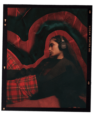 Frau mit Marshall Major V Black On-Ear-Kopfhörern vor einem roten, strukturierten Hintergrund.