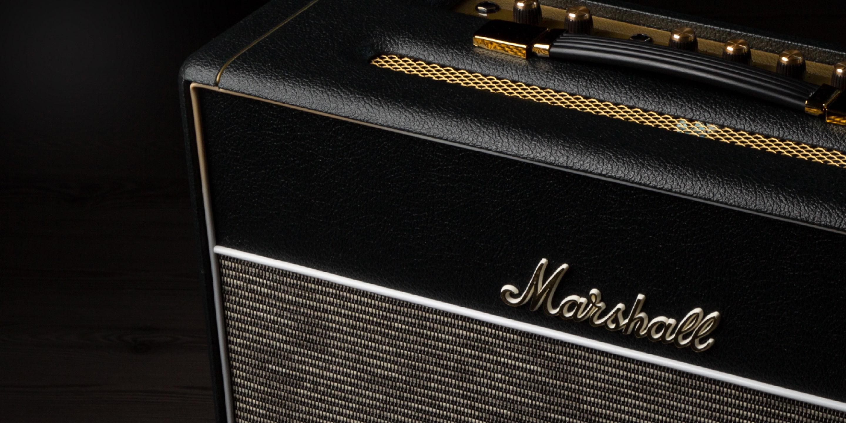 Focus on the control knobs and logo of the Marshall Black and Gold Handwired Amplifier.
