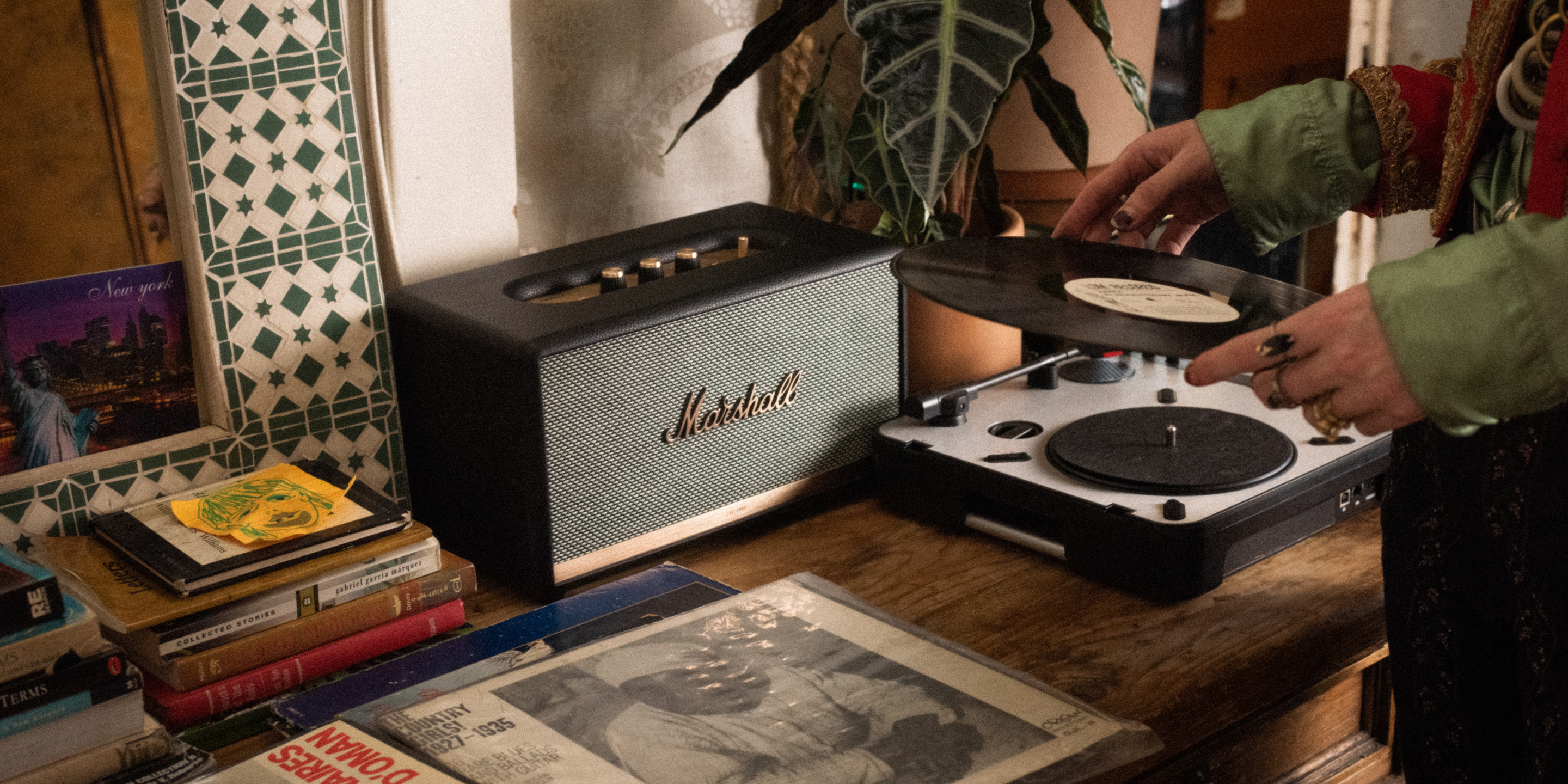 A person changing a vinyl on their record player connected to a Marshall speaker.